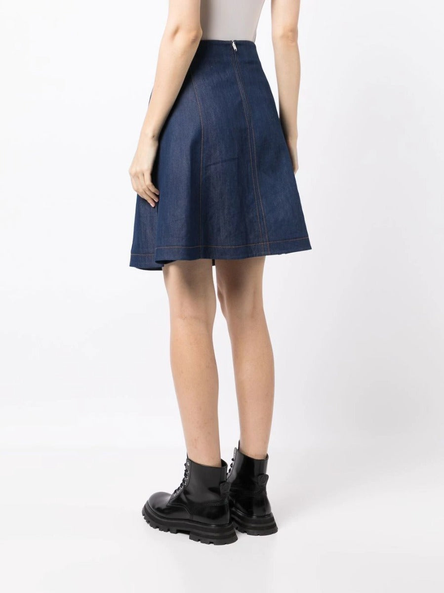 Balenciaga toggle-fastened A-line denim skirt with front pockets and metal button details, styled on a model.