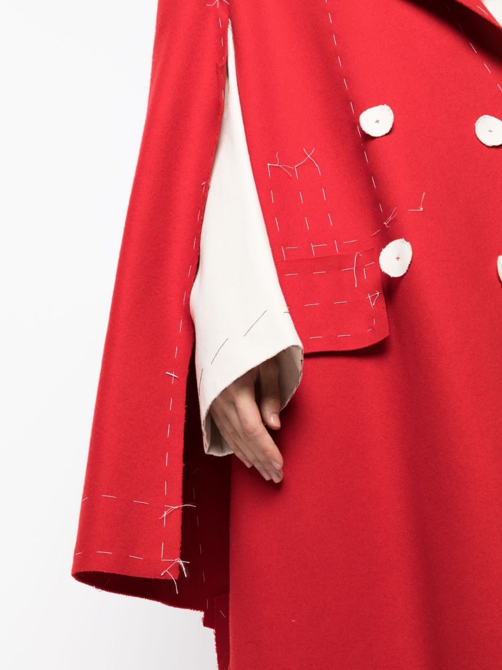 Maison Margiela deconstructed coat displayed on a hanger, showcasing its unique layered design and neutral tones.