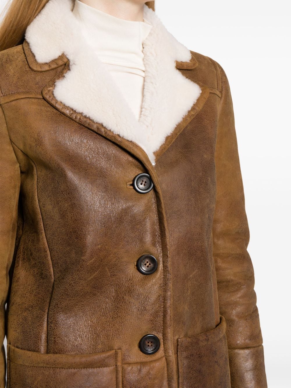 Prada shearling jacket with plush collar and tailored fit, displayed on a hanger against a neutral background.