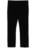 Black tapered trousers by The Row, stylish and tailored with a smooth fit, shown on a model against a neutral background.