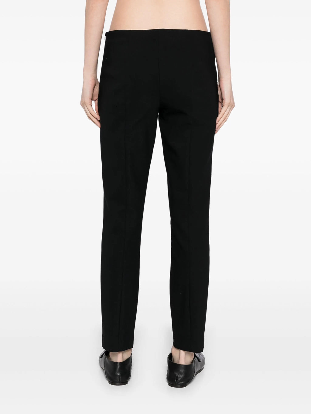Tapered textured black trousers from The Row, showing a sleek fit and subtle fabric pattern, on a neutral background.
