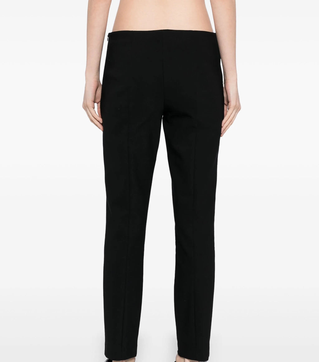 Black tapered trousers by The Row, featuring a sleek fit and minimalist design, shown on a model against a neutral background.
