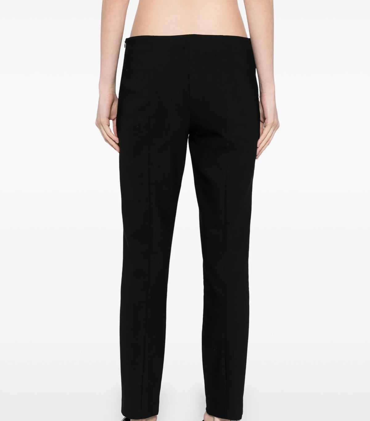 Black tapered trousers by The Row, featuring a sleek fit and minimalist design, shown on a model against a neutral background.