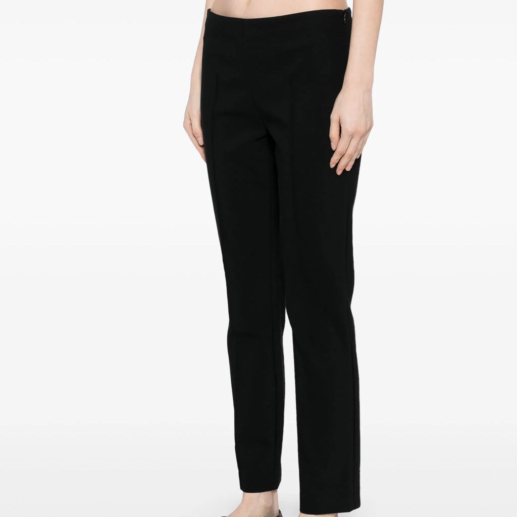 Black tapered trousers by The Row, featuring a slim fit and classic design, shown on a model in a casual setting.