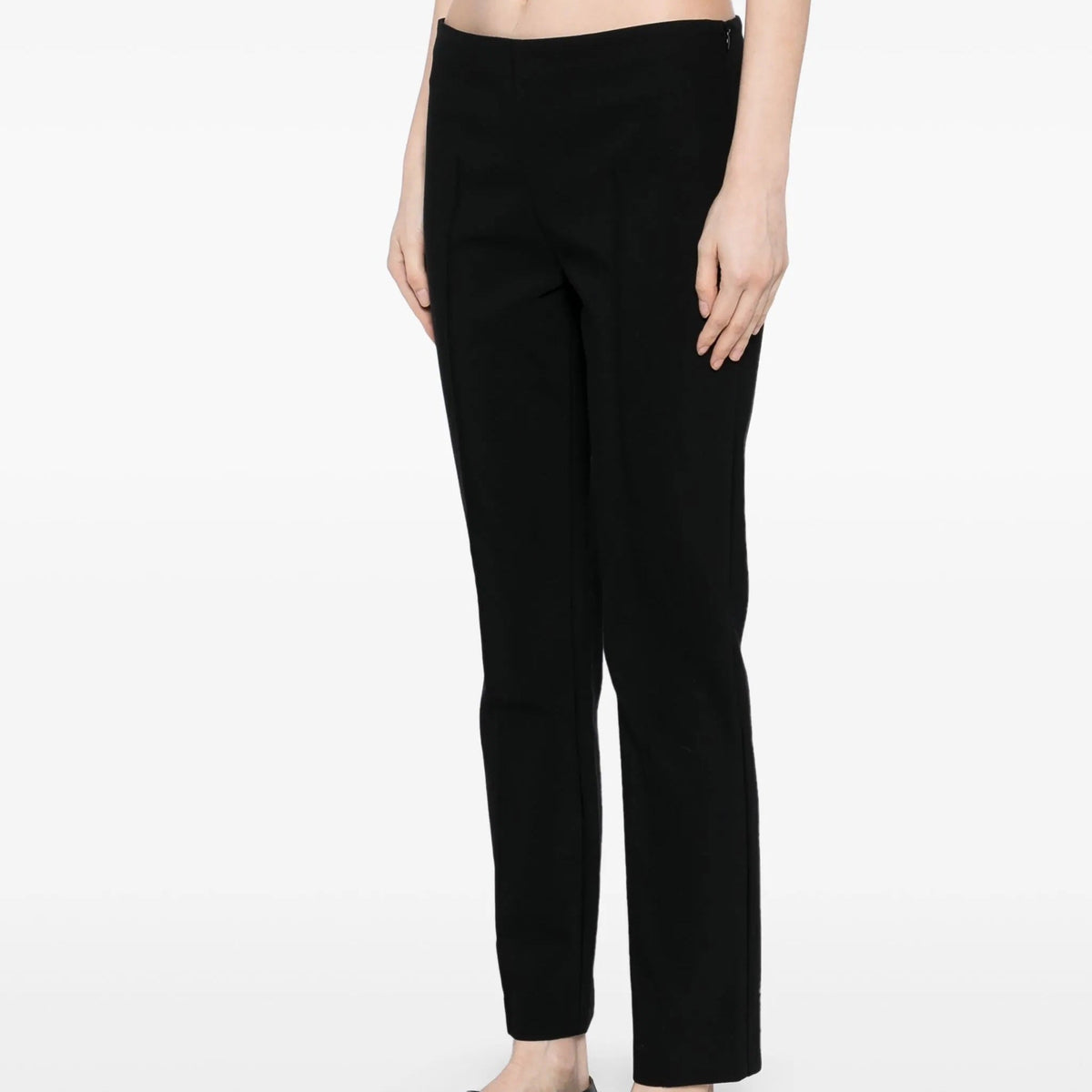 Black tapered trousers by The Row, featuring a slim fit and classic design, shown on a model in a casual setting.