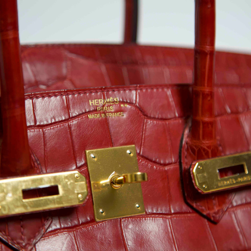 Hermès Birkin 35 red leather top handle bag with gold hardware, close-up view showing texture and luxurious details.