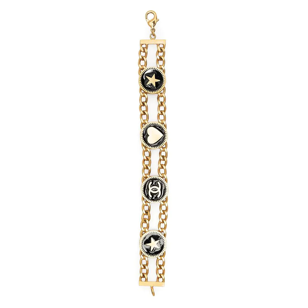 Chanel double chain charm bracelet with interlinked gold and silver chains and decorative charms on a neutral background.