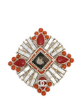 Chanel Crystals and Red Stones CC brooch featuring sparkling crystals and vibrant red stones on a elegant metal setting.
